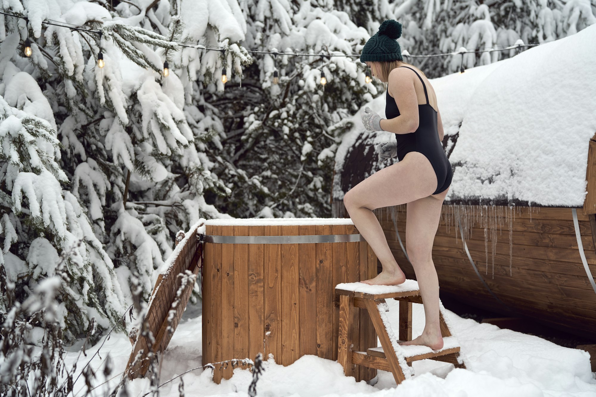Caucasian woman going into the barrel with cold water in winter outdoors